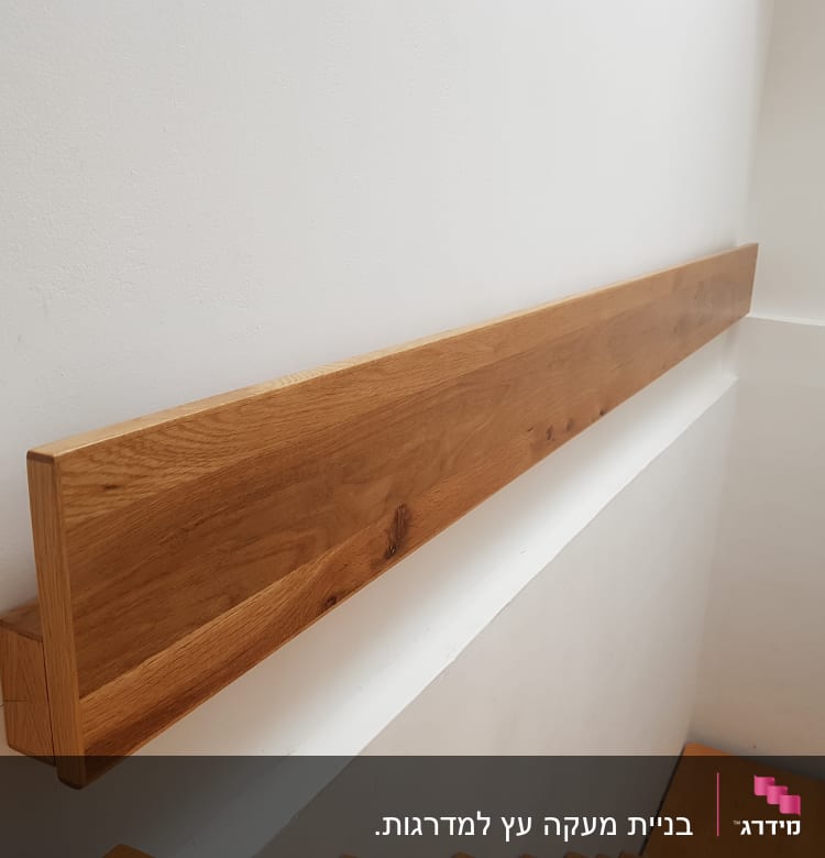 מעקה עץ מותקן על קיר לבן